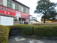 町中の街路樹の行き止まりに建てられた、文字が刻まれた黒い石板の写真
