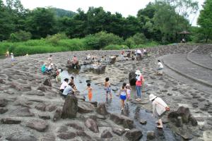 石ででこぼこしたなだらかな道に流れている浅い川で遊んでいる人たちの写真