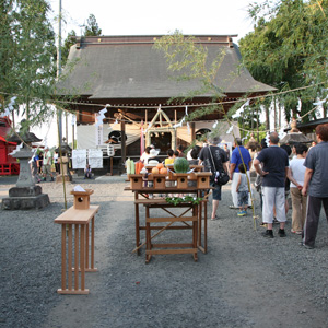 供物や飾り付けがされた神社の境内と訪れる人々の写真