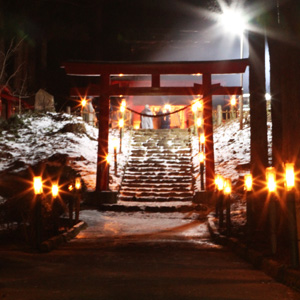 鳥居に続く道と雪が少し積もった階段に等間隔で明かりが設置されている写真