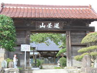 「山䑓蓮」と書かれた木製の看板が掲げられた赤い瓦葺の門の写真