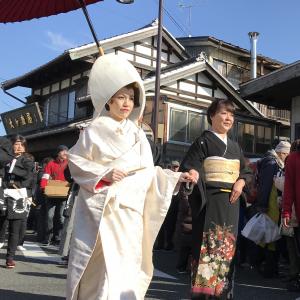 白無垢を着た女性と着物を着た女性が並んで町を歩いている写真