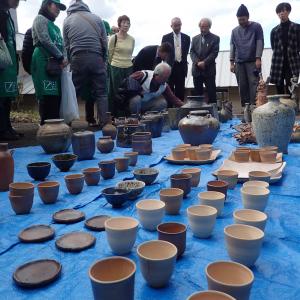 ブルーシートの上に並べられた陶器と、それを囲んで見る人々の写真