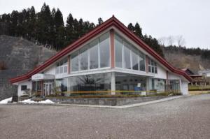 山肌を背景に建つ赤い屋根の建物の外観写真