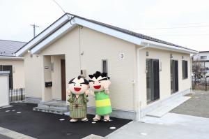 平家の吉田地区子育て支援住宅の前でマスコットキャラクターがポーズをとっている写真