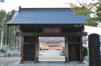青い屋根の門の奥に見えるお寺の写真
