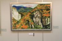 紅葉で色づいた山とその中にある切り立った崖の絵画