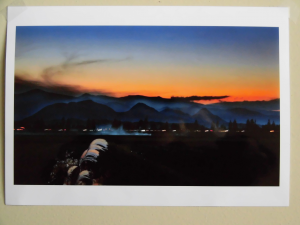 夕焼けと黒い山々、野原を背景に左側にススキが立っている写真