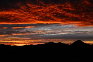 陰になった黒い山々と夕焼け、オレンジ色に色づいた雲の写真