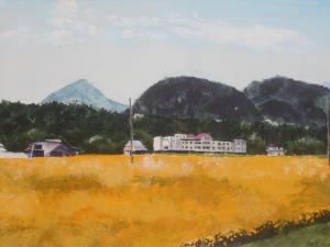 黄色に色づいた田んぼと奥に建物、山を描いた絵画