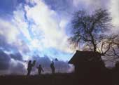 雲が一面に広がる空の下で凧揚げをして遊んでいる三人の子どもの写真