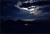 真っ暗な夜に雲の隙間から覗いた月の明かりを写した写真