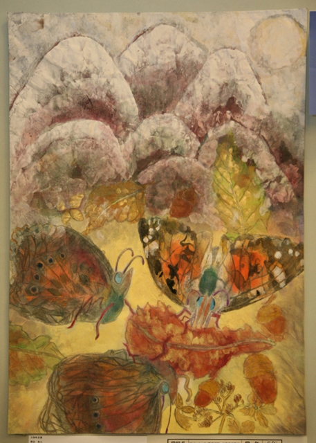 連なる山々の下で三匹の蝶が葉っぱやどんぐりの周りに集まっている絵画