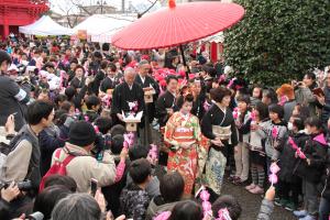 人々が両側に立つ道を着物の花嫁が歩く花嫁道中の写真