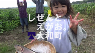 「しぜんと、えがお。大和町」ざるに載せられたお魚を持ってピースをする少女の動画サムネイル（2018「おおきな…」のYouTube動画へリンク）