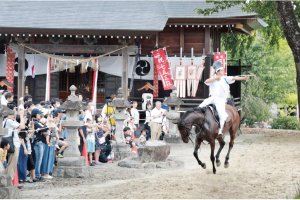 吉岡八幡神社で疾走する馬上から矢を放つ流鏑馬の射手の写真