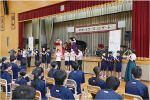 スクールコンサートでステージ上の仙台チェンバーアンサンブルに合わせて打楽器を演奏する中学生の写真