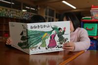 子供2人が「おおきなかぶ」の絵本を開いている写真